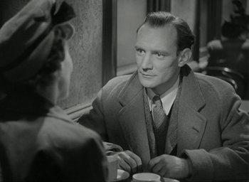 Movie still from “Brief Encounter” (1945), directed by David Lean – An old photo of a man and a woman sitting at a table; Close Up shot, Over the shoulder angle