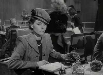 Movie still from “Brief Encounter” (1945), directed by David Lean – A woman sitting at a table with a book in front of her; Medium shot, Low angle