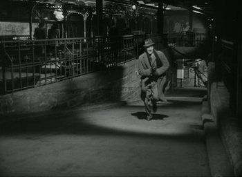 Movie still from “Brief Encounter” (1945), directed by David Lean – An old photo of a man in a hat and a suit; Wide shot, High angle