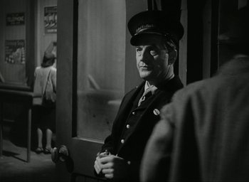 Movie still from “Brief Encounter” (1945), directed by David Lean – Black and white photograph of a man in a uniform; Medium shot, Over the shoulder angle