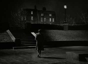 Movie still from “Brief Encounter” (1945), directed by David Lean – A woman standing in front of a building at night; Extreme Wide shot, Low angle