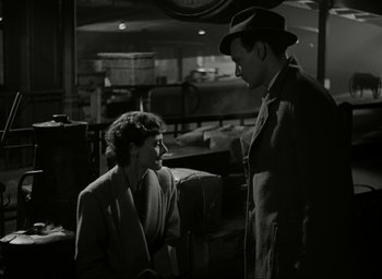 Movie still from “Brief Encounter” (1945), directed by David Lean – A man and a woman talking in front of luggage; Medium shot, High angle