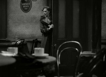 Movie still from “Brief Encounter” (1945), directed by David Lean – A black and white photo of a woman standing in front of a table; Wide shot, High angle