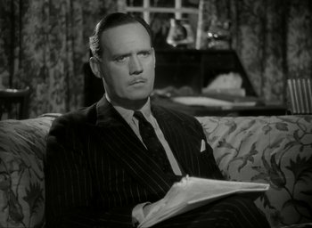 Movie still from “Brief Encounter” (1945), directed by David Lean – A man sitting on top of a couch in a room; Close Up shot, High angle