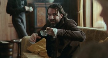 Movie still from “Bright Star” (2009), directed by Jane Campion – A man sitting on a couch playing a video game; Medium shot, High angle