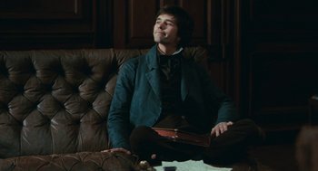 Movie still from “Bright Star” (2009), directed by Jane Campion – A man sitting on top of a brown leather couch; Medium shot, Low angle