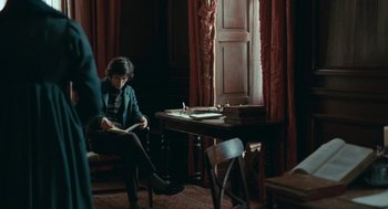 Movie still from “Bright Star” (2009), directed by Jane Campion – A woman sitting at a table reading a book; Medium shot, Over the shoulder angle