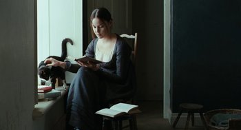 Movie still from “Bright Star” (2009), directed by Jane Campion – A woman sitting in a chair looking at a book; Medium shot, Over the shoulder angle