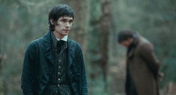 Movie still from “Bright Star” (2009), directed by Jane Campion – A man in a suit and tie standing next to a tree; Medium shot, Over the shoulder angle