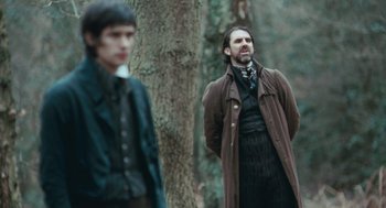 Movie still from “Bright Star” (2009), directed by Jane Campion – Two men standing next to each other near a tree; Medium shot, Over the shoulder angle