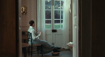 Movie still from “Bright Star” (2009), directed by Jane Campion – A woman sitting on a chair in front of an open door; Wide shot, High angle