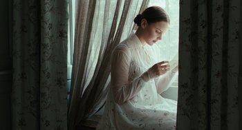 Movie still from “Bright Star” (2009), directed by Jane Campion – A woman in a white dress sitting in front of a window; Medium shot, High angle