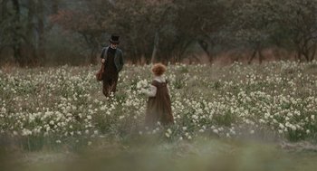 A man and a woman walking through a field of white flowers