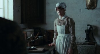 Movie still from “Bright Star” (2009), directed by Jane Campion – A woman in a kitchen wearing an apron and hat; Medium shot, Over the shoulder angle