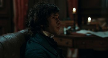 Movie still from “Bright Star” (2009), directed by Jane Campion – A man with long curly hair sitting in a room; Close Up shot, Over the shoulder angle