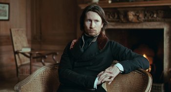 Movie still from “Bright Star” (2009), directed by Jane Campion – A man sitting in a chair with his arms crossed; Close Up shot, Over the shoulder angle