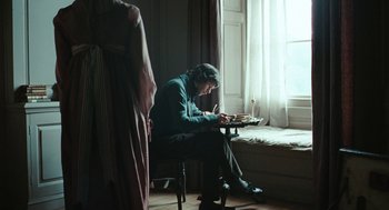 Movie still from “Bright Star” (2009), directed by Jane Campion – An older woman sitting in a chair writing on a piece of paper in front of a window; Wide shot, Over the shoulder angle