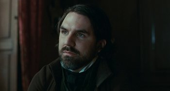 Movie still from “Bright Star” (2009), directed by Jane Campion – A man with long hair and a beard wearing a suit; Close Up shot, Over the shoulder angle