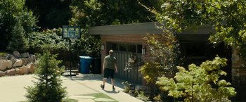 Movie still from “Brigsby Bear” (2017), directed by Dave McCary – A man walking down a sidewalk next to a building; Wide shot, Low angle