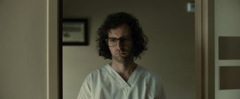 A man in a white shirt wearing glasses and looking at the camera