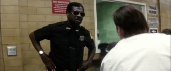 Movie still from “Bringing Out the Dead” (1999), directed by Martin Scorsese – A police officer talking to a man in sunglasses; Medium shot, Low angle