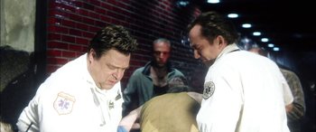 Movie still from “Bringing Out the Dead” (1999), directed by Martin Scorsese – A group of men standing next to each other in front of a brick wall; Medium shot, Over the shoulder angle