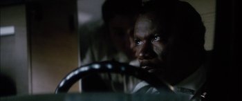 Movie still from “Bringing Out the Dead” (1999), directed by Martin Scorsese – A man looking at the camera while holding a steering wheel in front of him; Close Up shot, Over the shoulder angle