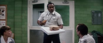 Movie still from “Bringing Out the Dead” (1999), directed by Martin Scorsese – A police officer holding a sandwich and a box of food; Medium shot, Low angle