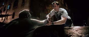 Movie still from “Bringing Out the Dead” (1999), directed by Martin Scorsese – A man in a police uniform holding a knife to another man's arm; Medium shot, Low angle