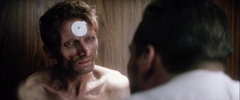 Movie still from “Bringing Out the Dead” (1999), directed by Martin Scorsese – A man is looking into a mirror with a patch on his forehead; Close Up shot, Over the shoulder angle