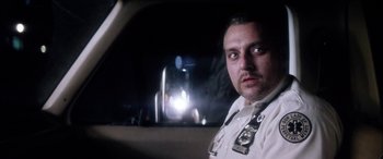Movie still from “Bringing Out the Dead” (1999), directed by Martin Scorsese – A man in a police uniform sitting in the back of a car; Close Up shot, Low angle