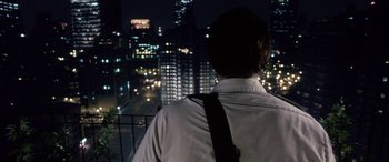 Movie still from “Bringing Out the Dead” (1999), directed by Martin Scorsese – A man standing on a balcony looking out at a city at night; Wide shot, Over the shoulder angle