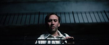 Movie still from “Bringing Out the Dead” (1999), directed by Martin Scorsese – A man standing behind a metal fence looking up; Close Up shot, Low angle