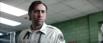 Movie still from “Bringing Out the Dead” (1999), directed by Martin Scorsese – A man in a white shirt is standing in front of a brick wall; Close Up shot, Low angle