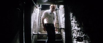 Movie still from “Bringing Out the Dead” (1999), directed by Martin Scorsese – A man standing on a set of stairs in the dark; Medium shot, Low angle