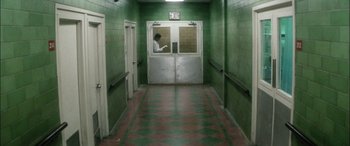 Movie still from “Bringing Out the Dead” (1999), directed by Martin Scorsese – A person standing in a hallway with a door open; Wide shot, High angle