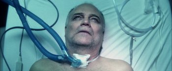 Movie still from “Bringing Out the Dead” (1999), directed by Martin Scorsese – A man laying in a hospital bed with an oxygen mask attached to his neck; Close Up shot, Overhead angle