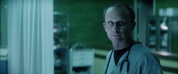 Movie still from “Bringing Out the Dead” (1999), directed by Martin Scorsese – A man wearing glasses and a lab coat in a room; Close Up shot, Low angle