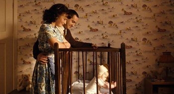 Movie still from “Bronson” (2008), directed by Nicolas Winding Refn – A man , woman , and a baby in a wooden crib; Medium shot, High angle