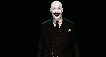 Movie still from “Bronson” (2008), directed by Nicolas Winding Refn – A man in a suit and a clown mask; Medium shot, Low angle
