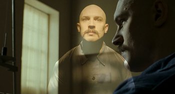 Movie still from “Bronson” (2008), directed by Nicolas Winding Refn – A man with a bald head is reflected in a mirror; Close Up shot, Low angle