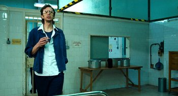 Movie still from “Bronson” (2008), directed by Nicolas Winding Refn – A man standing next to a table with a pot on it; Medium shot, Low angle