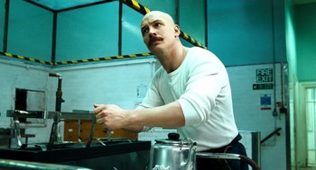 Movie still from “Bronson” (2008), directed by Nicolas Winding Refn – A man with a bald head is holding a knife; Medium shot, Low angle
