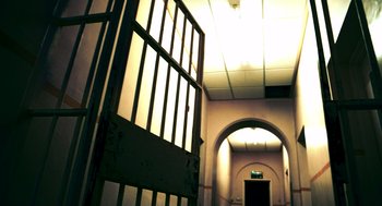 Movie still from “Bronson” (2008), directed by Nicolas Winding Refn – An open door leading to a hallway with a light shining on it; Wide shot, Low angle