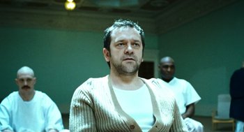 Movie still from “Bronson” (2008), directed by Nicolas Winding Refn – A man in a white shirt and striped sweater; Medium shot, Low angle