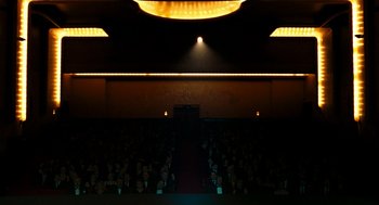 Movie still from “Bronson” (2008), directed by Nicolas Winding Refn – A crowd of people sitting in an auditorium at night; Extreme Wide shot, Low angle