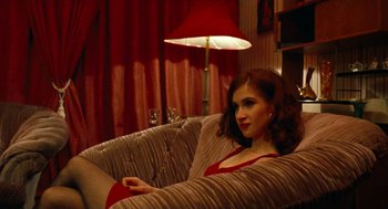 Movie still from “Bronson” (2008), directed by Nicolas Winding Refn – A woman sitting on a couch in a living room; Medium shot, High angle