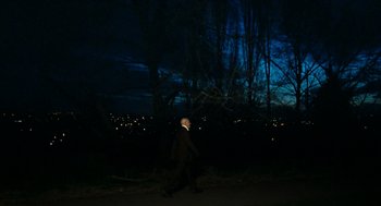 Movie still from “Bronson” (2008), directed by Nicolas Winding Refn – A man in a black suit is walking in the dark; Extreme Wide shot, Low angle