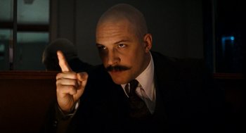 Movie still from “Bronson” (2008), directed by Nicolas Winding Refn – A man with a bald head wearing a suit and tie; Close Up shot, Low angle