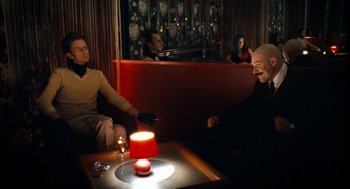 Movie still from “Bronson” (2008), directed by Nicolas Winding Refn – Two men sitting at a table in a restaurant; Medium shot, Over the shoulder angle